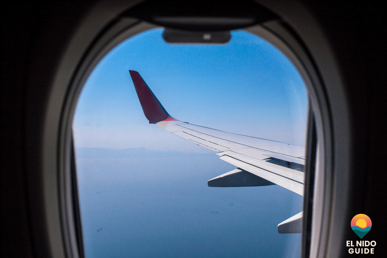 View from an airplane window over the wing at sunrise, clouds below, on a long-haul flight to the Philippines.