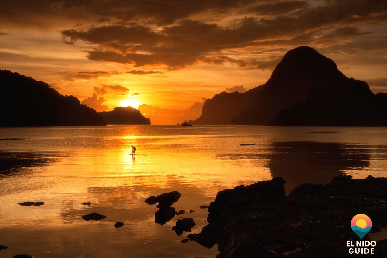 Golden sunset over El Nido bay with bangka boats silhouetted on calm water.